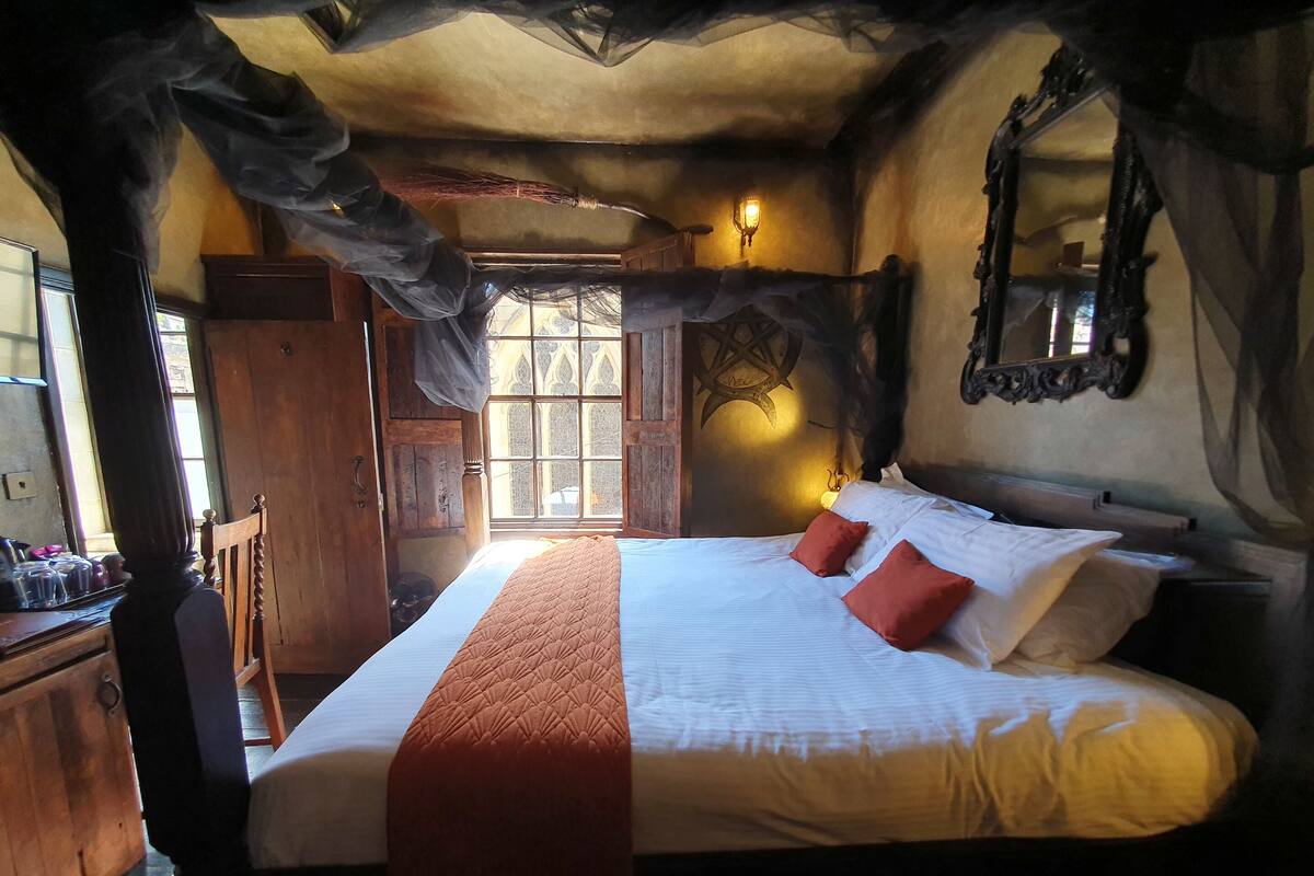 A bedroom with a large bed, a wooden wardrobe, and a window with curtains.