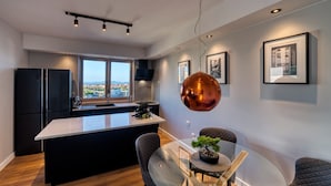 A modern kitchen with a central island, black cabinetry, and a view through large windows. - Penthouse Luxury Suite (Zadar)