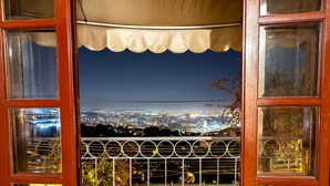 A view through a wooden-framed window with a metal railing, overlooking a cityscape at night. - Inn House Santa Teresa (Rio de Janeiro)