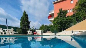 Ein klares Schwimmbecken mit Liegestühlen und einem Gebäude im Hintergrund.