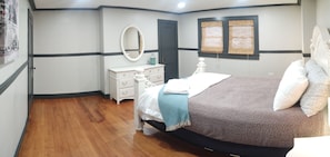 Un dormitorio con cama, cómoda, espejo y ventana con persianas.