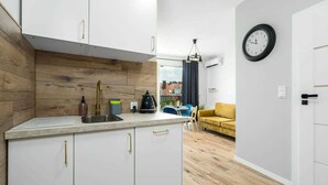 A modern kitchen with white cabinets and a wooden backsplash, a coffee machine, and a sink.