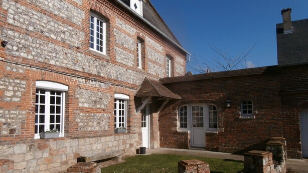Un bâtiment en pierre de deux étages, doté de nombreuses fenêtres et d’un petit jardin.