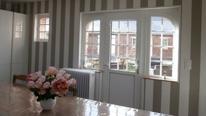 Une pièce aux murs rayés, avec une table en bois et un vase de fleurs.
