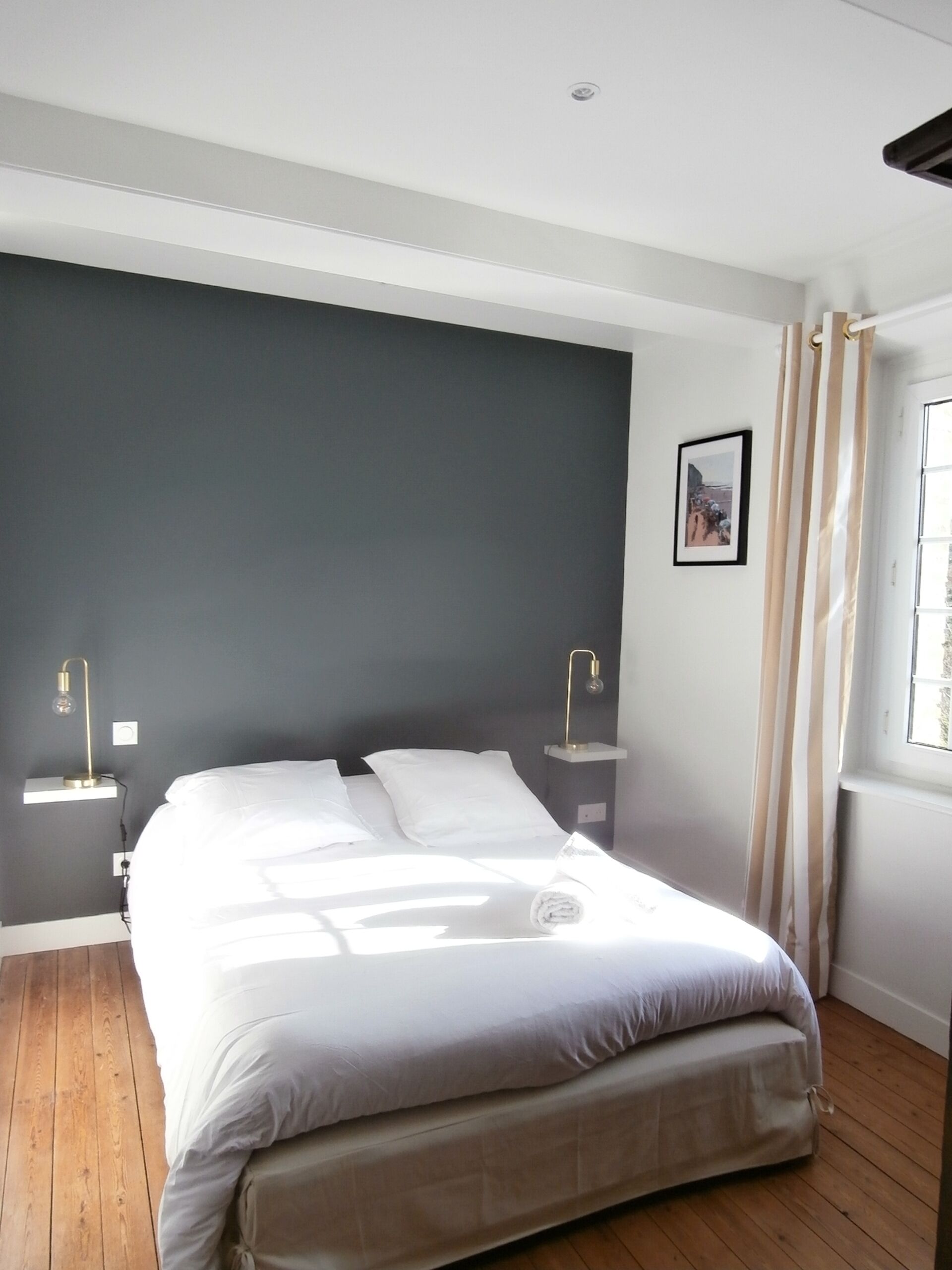 Une chambre moderne avec un grand lit, des tables de chevet et une fenêtre avec des rideaux.