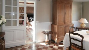 Une pièce avec un sol à carreaux, une armoire en bois, une table avec une lampe et une chaise.