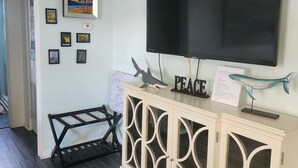 Una sala de estar con un televisor de pantalla plana montado en la pared, un mueble de madera con detalles decorativos y varias imágenes enmarcadas en la pared.