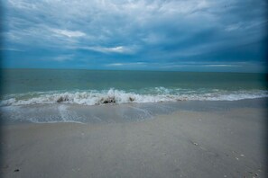 A beach with waves gently lapping at the shore under a cloudy sky. - SANDY TUNDRA TOWNHOUSE, WATER-VIEWS, BOAT SLIP, PRIVATE BEACH, CLUB ACCESS (Captiva)