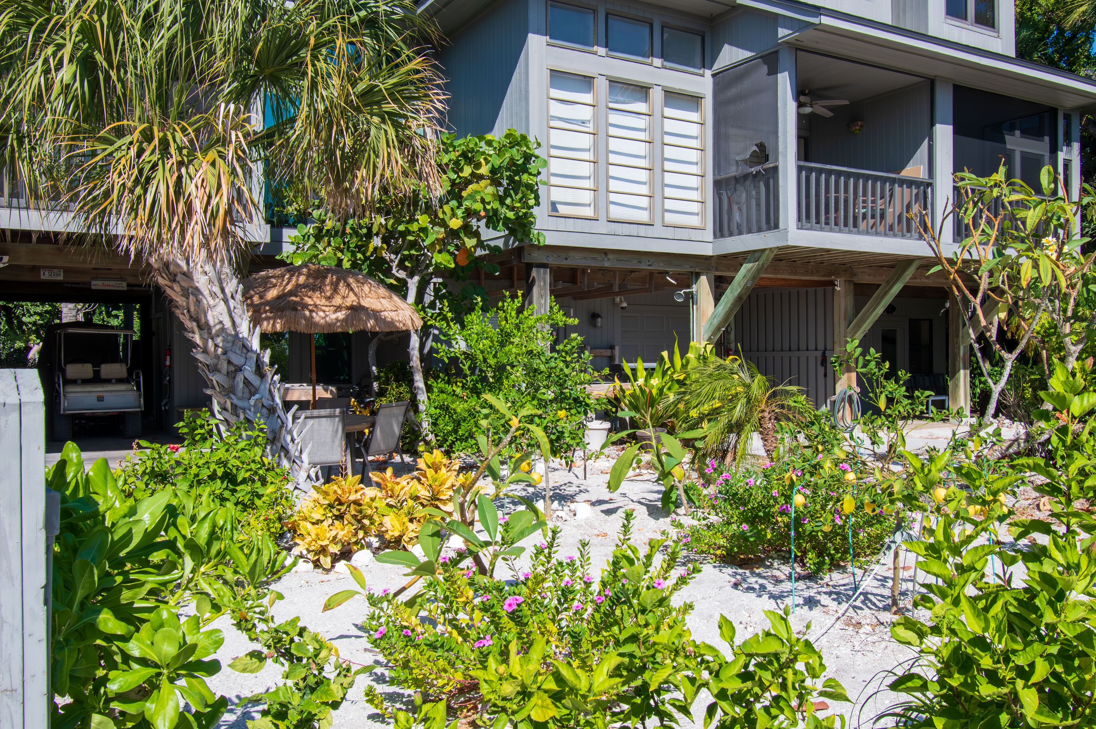 Une propriété située en bord de mer, dotée d’un patio couvert, d’une piscine et d’une variété de plantes tropicales.