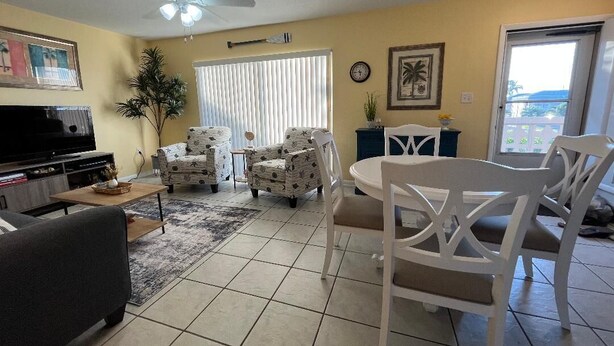 A living room with a sofa, two armchairs, a dining table, and a TV. - Private Beach Living (Cocoa Beach)