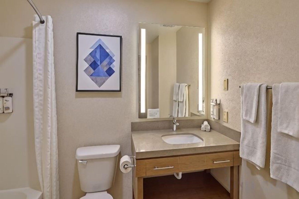 A bathroom with a toilet, sink, mirror, and towel rack.