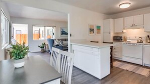 Une cuisine moderne avec des meubles blancs, un îlot central et un coin repas comprenant une table et des chaises.