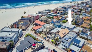 Vue aérienne d’une zone résidentielle côtière, avec des maisons, une plage et l’océan.
