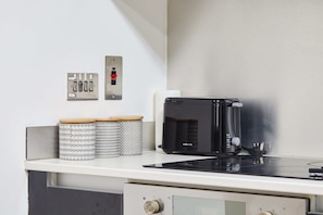 A kitchen with a black toaster, a white countertop, and a stainless steel switchboard with a red button. - LS1 Perfect For Business Travellers & Relocations - 4 Beds, 2 Baths - FREE WiFi (Leeds)