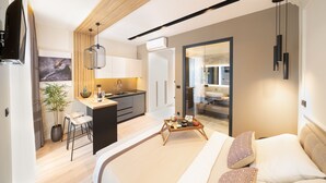 A modern hotel room with a large bed, a small kitchenette, a dining area, and a bathroom. - Premium apartments with balcony (Rijeka)