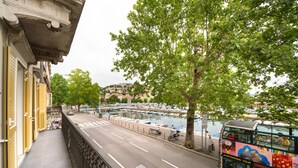 A street view with a double-decker bus, a tree-lined sidewalk, and a marina in the background. - Premium apartments with balcony (Rijeka)