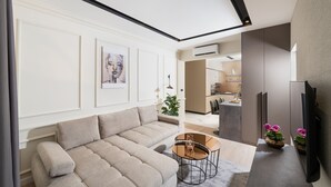 A modern living room with a beige sofa, a glass coffee table, and a flat-screen TV. - Premium apartments with balcony (Rijeka)