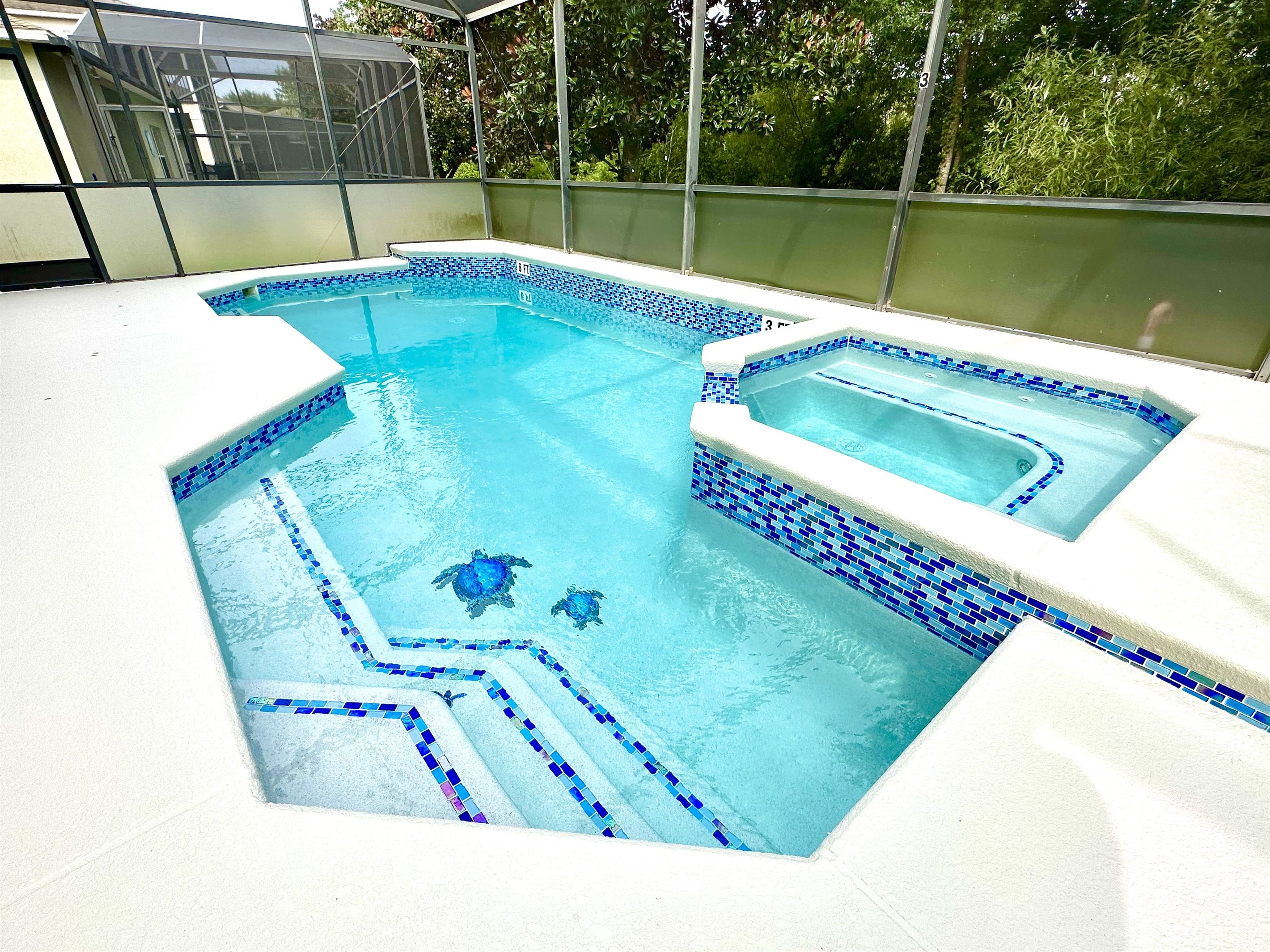 A swimming pool with blue mosaic tiles and a separate hot tub area.