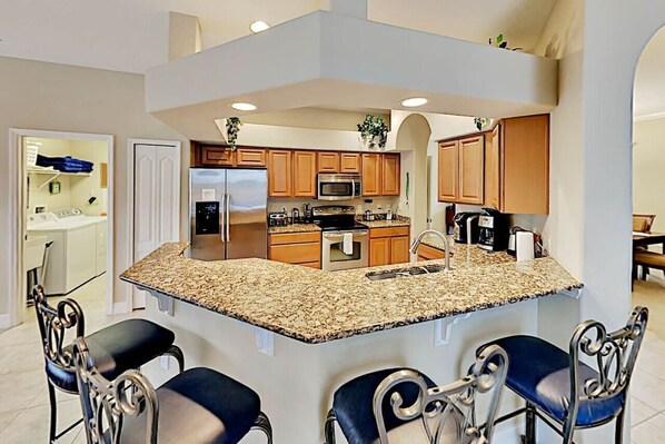 A modern kitchen with granite countertops, stainless steel appliances, and wooden cabinets.