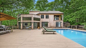 A modern two-story house with a wooden exterior, a swimming pool, and a deck with lounge chairs. - Modern Newly Renovated Summer Get Away  (East Hampton)