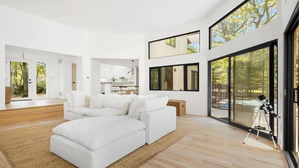 A modern living room with a sectional sofa, a large window, and a telescope on a tripod. - Modern Newly Renovated Summer Get Away  (East Hampton)