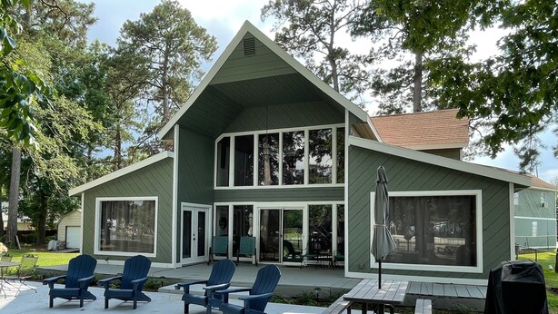 Une maison à deux étages dotée d’un patio couvert comprenant un espace salon extérieur et un barbecue.