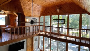 Une cabane dotée d’une chambre à coucher située en mezzanine, d’un coin repas et de grandes fenêtres offrant une vue sur l’extérieur.