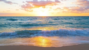 Una playa con olas al atardecer.