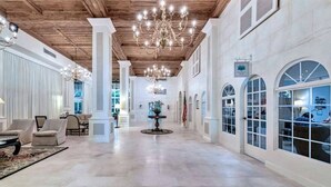 Un vestíbulo amplio con techos altos, candelabros y ventanas arqueadas.