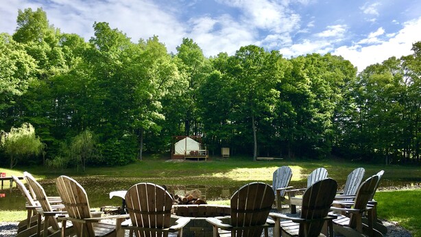 Un espace aménagé au bord du lac, avec des chaises Adirondack et une petite tente.