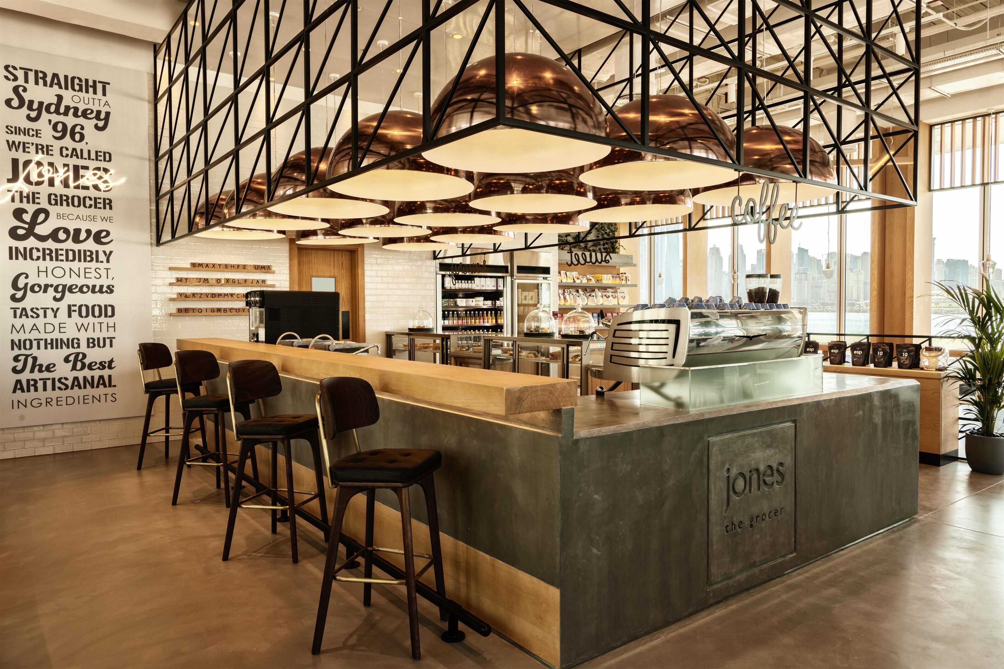 A modern cafe interior with a bar area, seating, and a city view.
