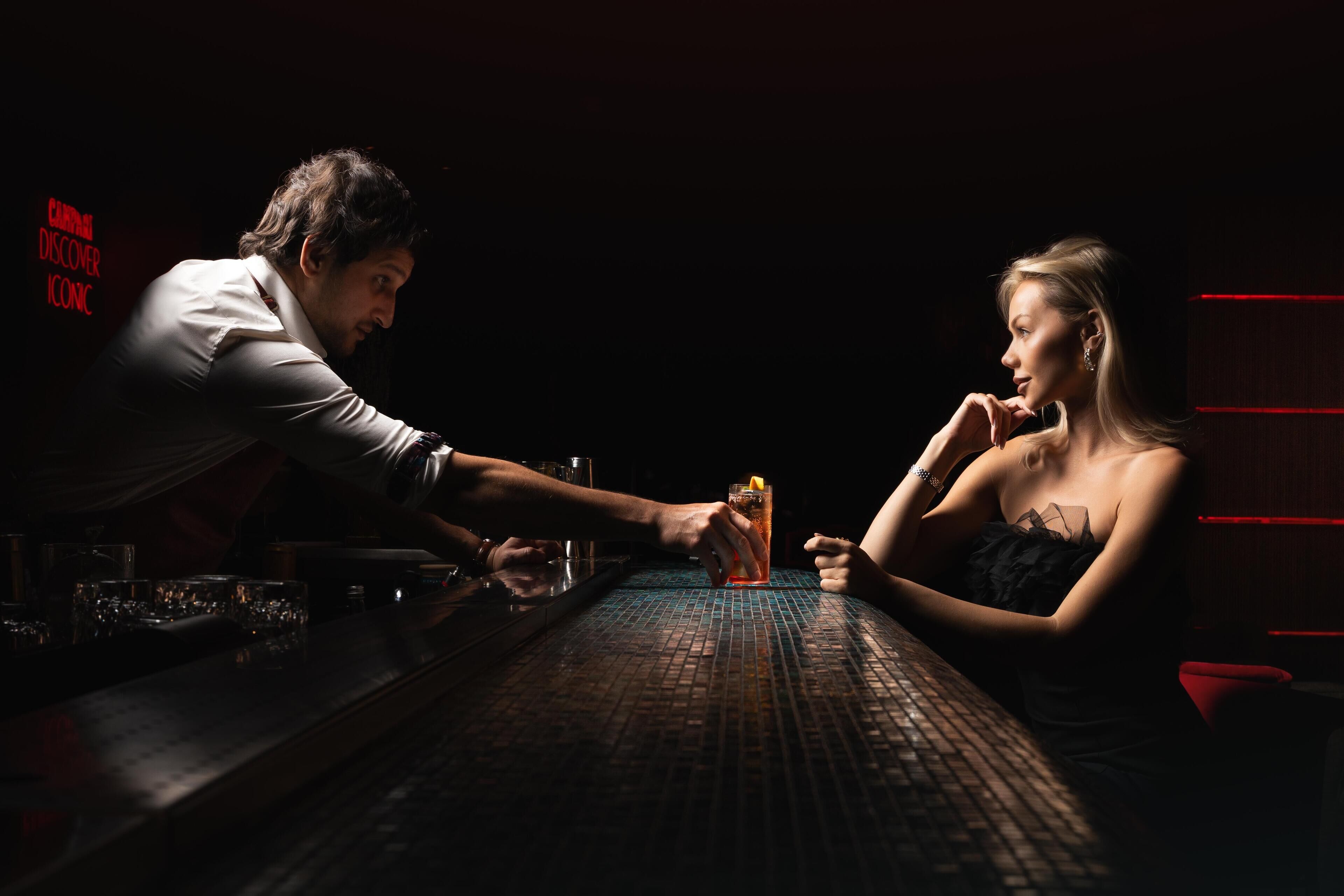 A bar setting with a person pouring a drink into a glass.