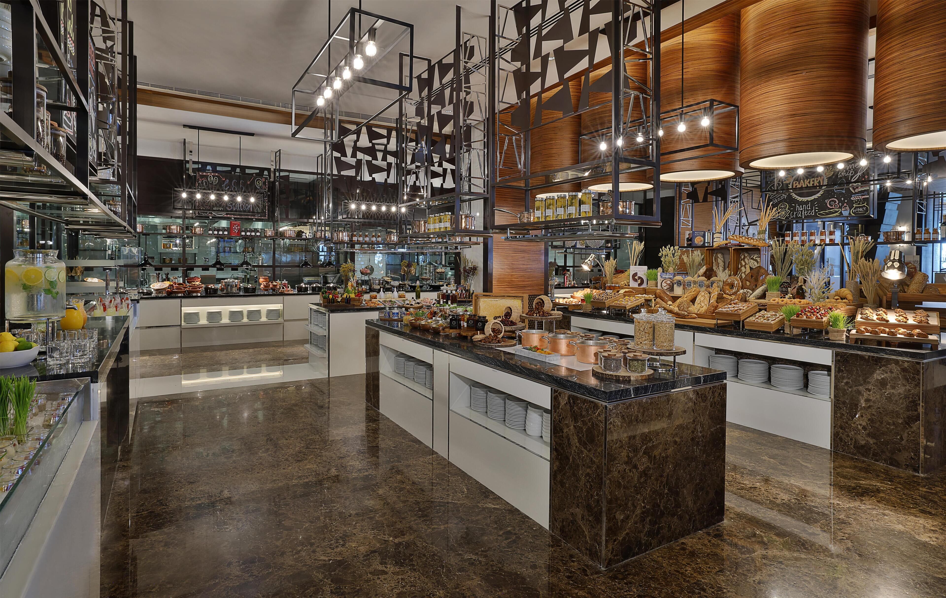 A modern kitchen with marble countertops, stainless steel appliances, and a central island with food displays.