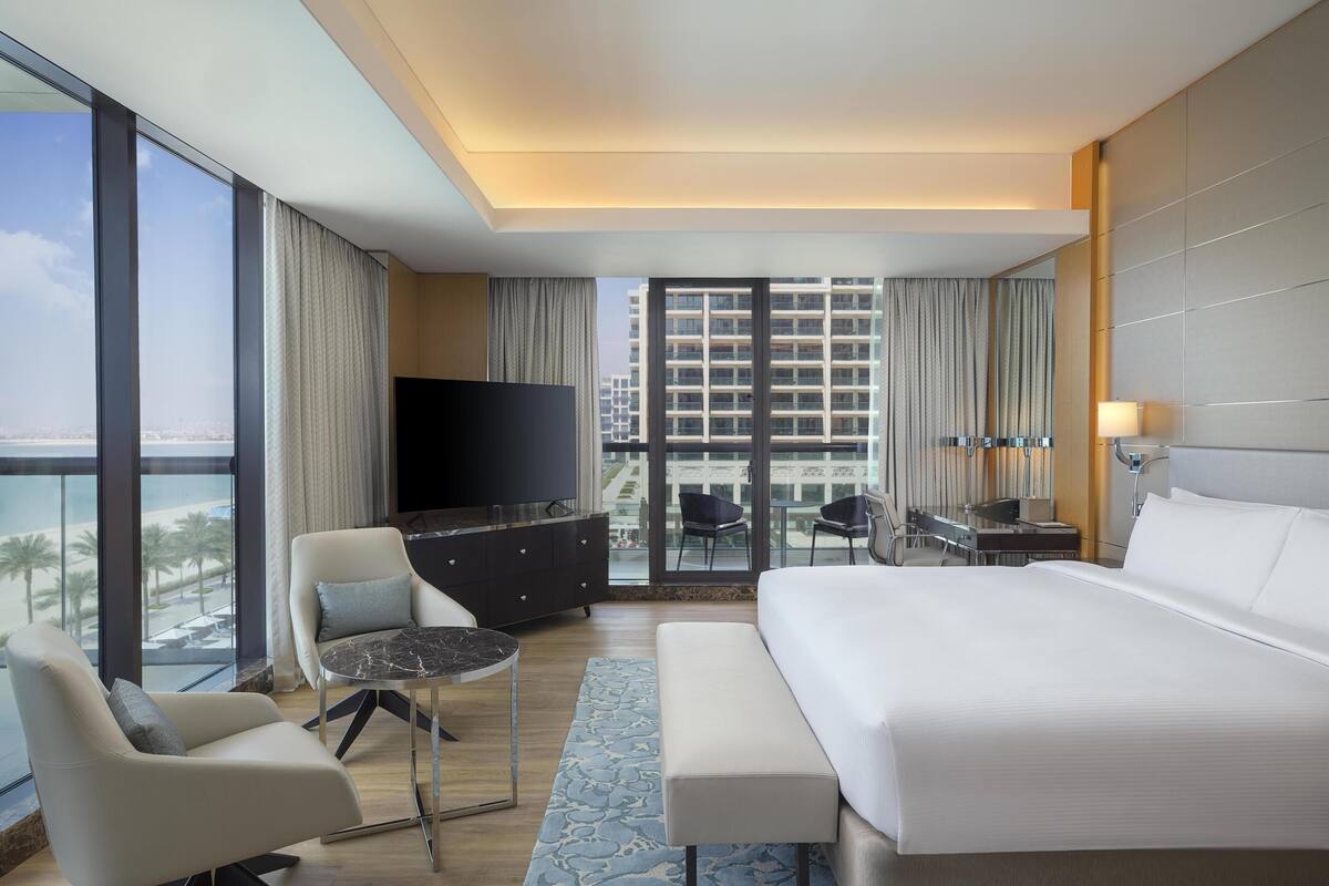 Ein modernes Hotelzimmer mit einem großen Bett, einem Fernseher, einem Schreibtisch und Blick auf die Stadt.