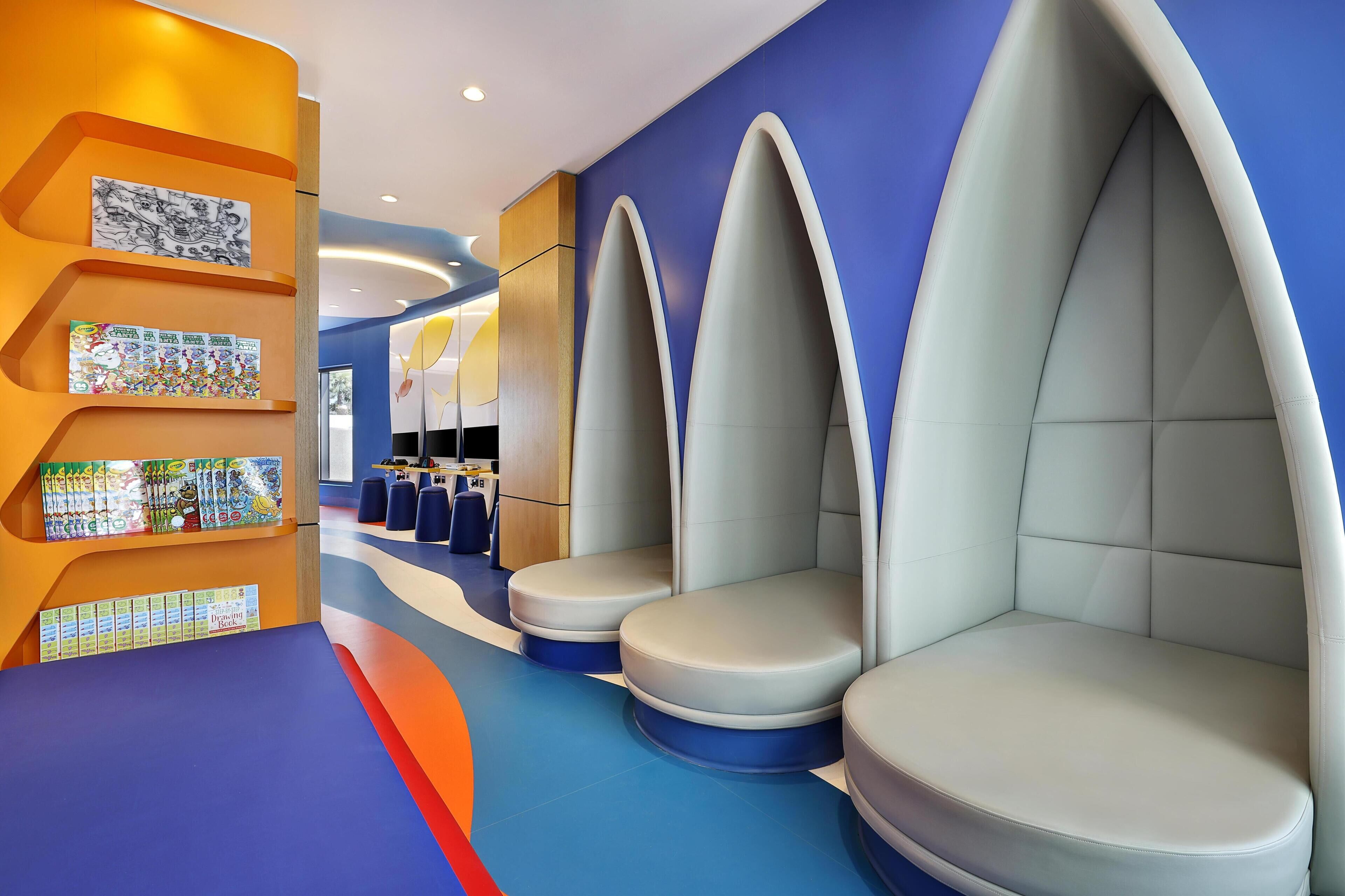 A modern interior with seating areas, a colorful wall with artwork, and a blue floor.