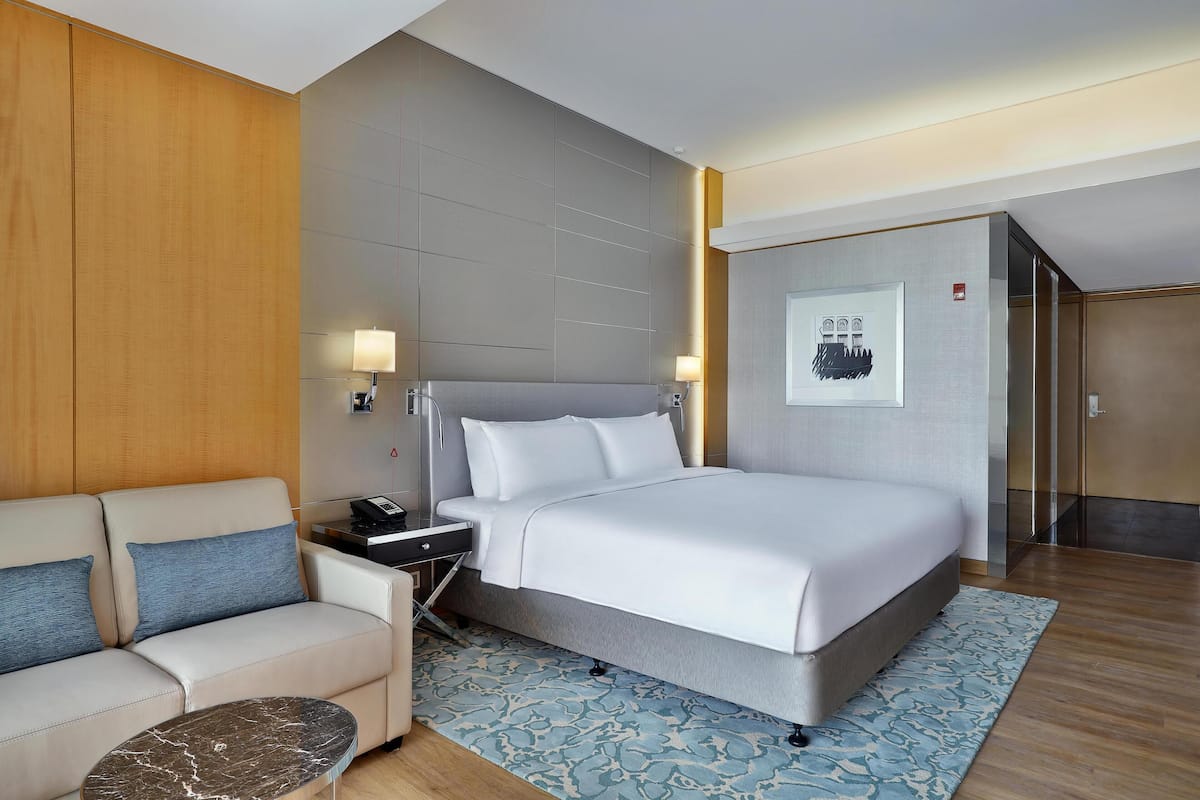 Ein modernes Hotelzimmer mit Bett, einer Couch, einem Nachttisch und einem Schreibtisch.