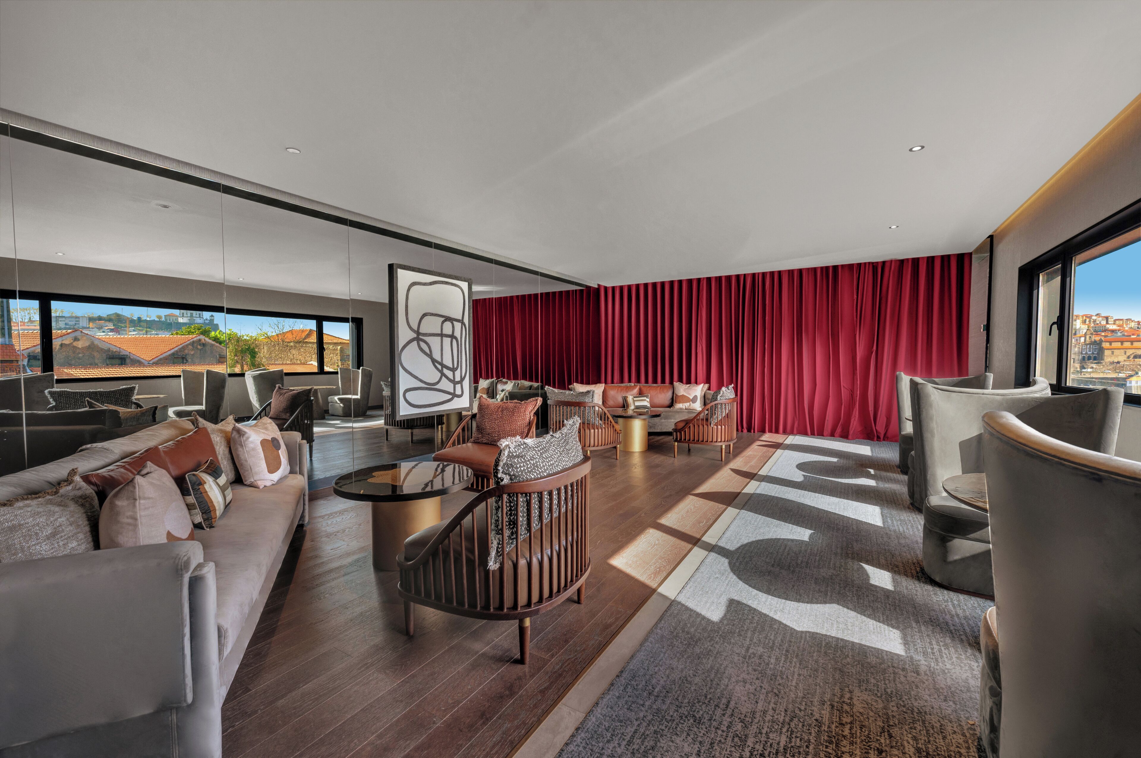Una habitación de hotel moderna con un ventanal grande, una cortina roja y vistas a la ciudad.
