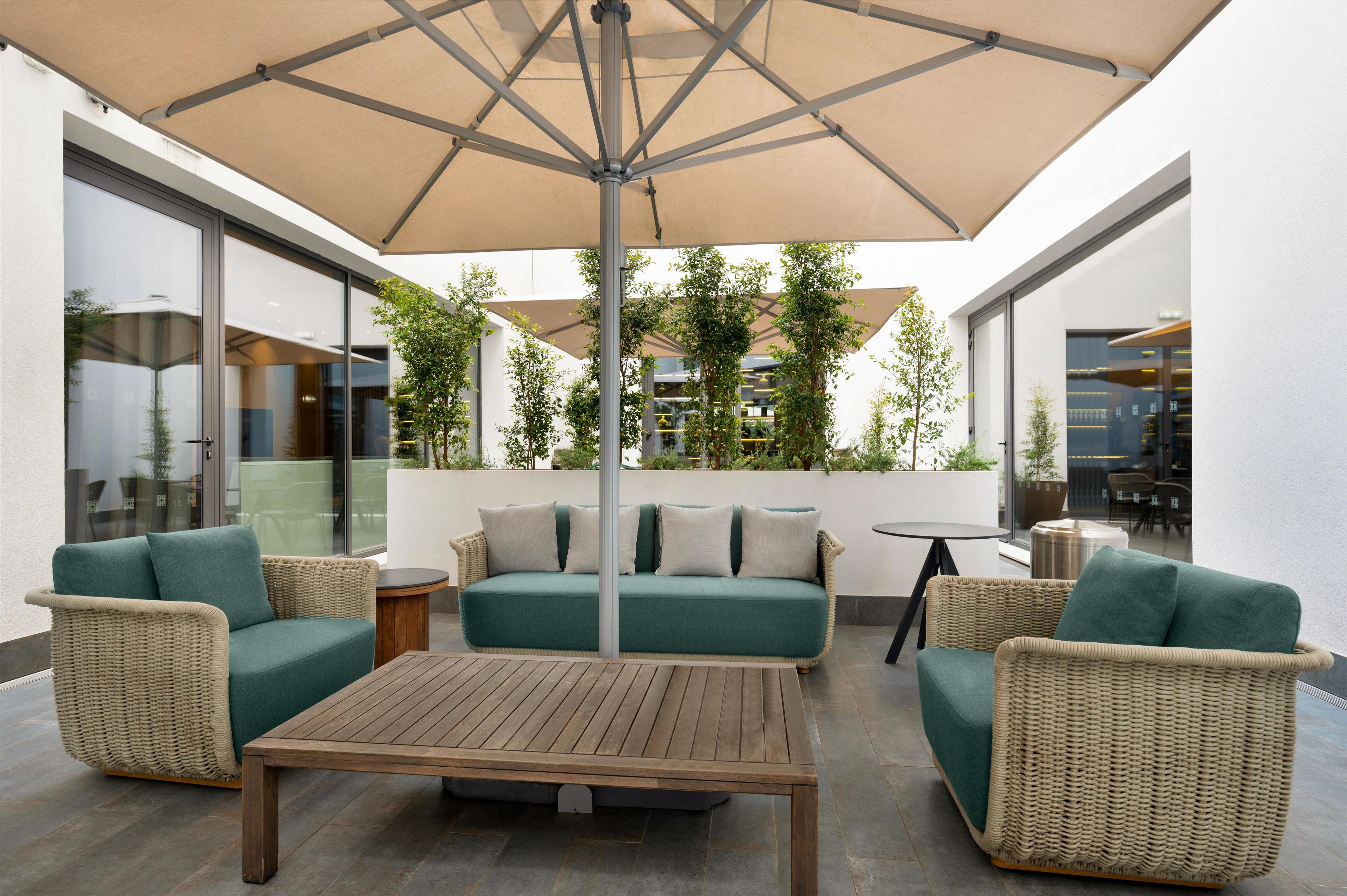 An outdoor seating area with a table, two sofas, and an umbrella.