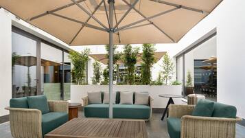 An outdoor seating area with a table, two sofas, and an umbrella.