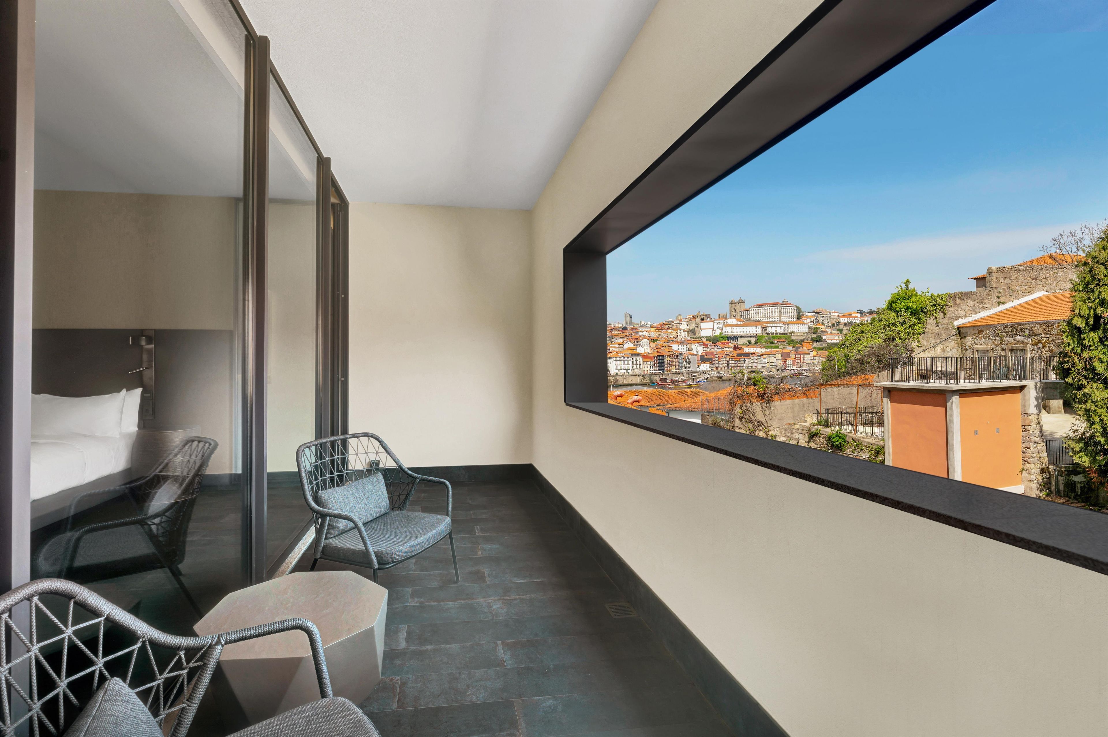 Un balcon avec un lit, deux chaises et une vue sur le paysage urbain.