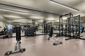 A modern gym with various exercise equipment, including weight machines and free weights, and a large mirror reflecting the space. - Hilton Porto Gaia (Vila Nova de Gaia)