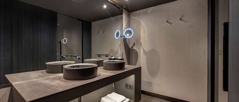 A modern bathroom with a dark wood vanity, two sinks, and a mirror.