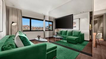 A modern living room with green sofas, a flat-screen TV, and a city view.