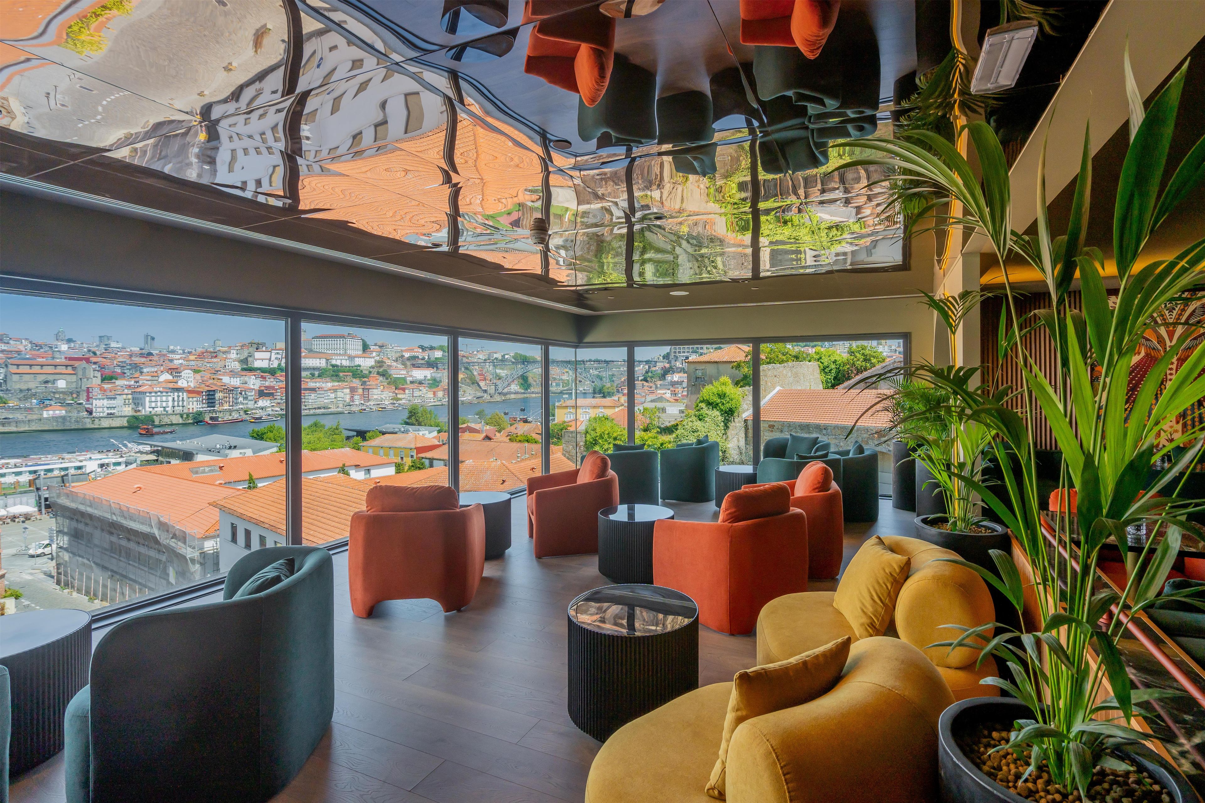 A modern interior with a high ceiling, large windows, and a view of a cityscape.