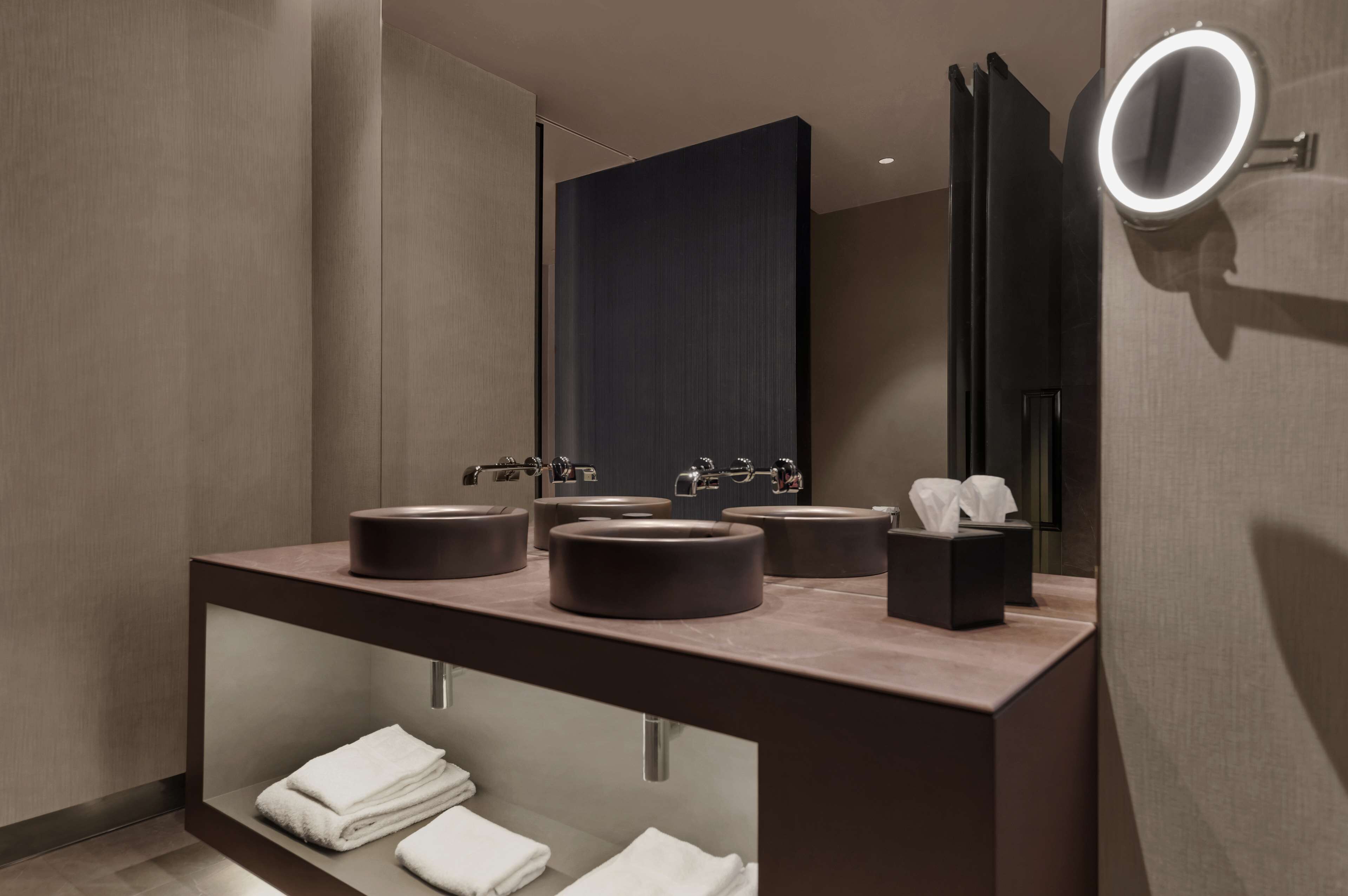 A modern bathroom with a large mirror, multiple sinks, and a towel rack.