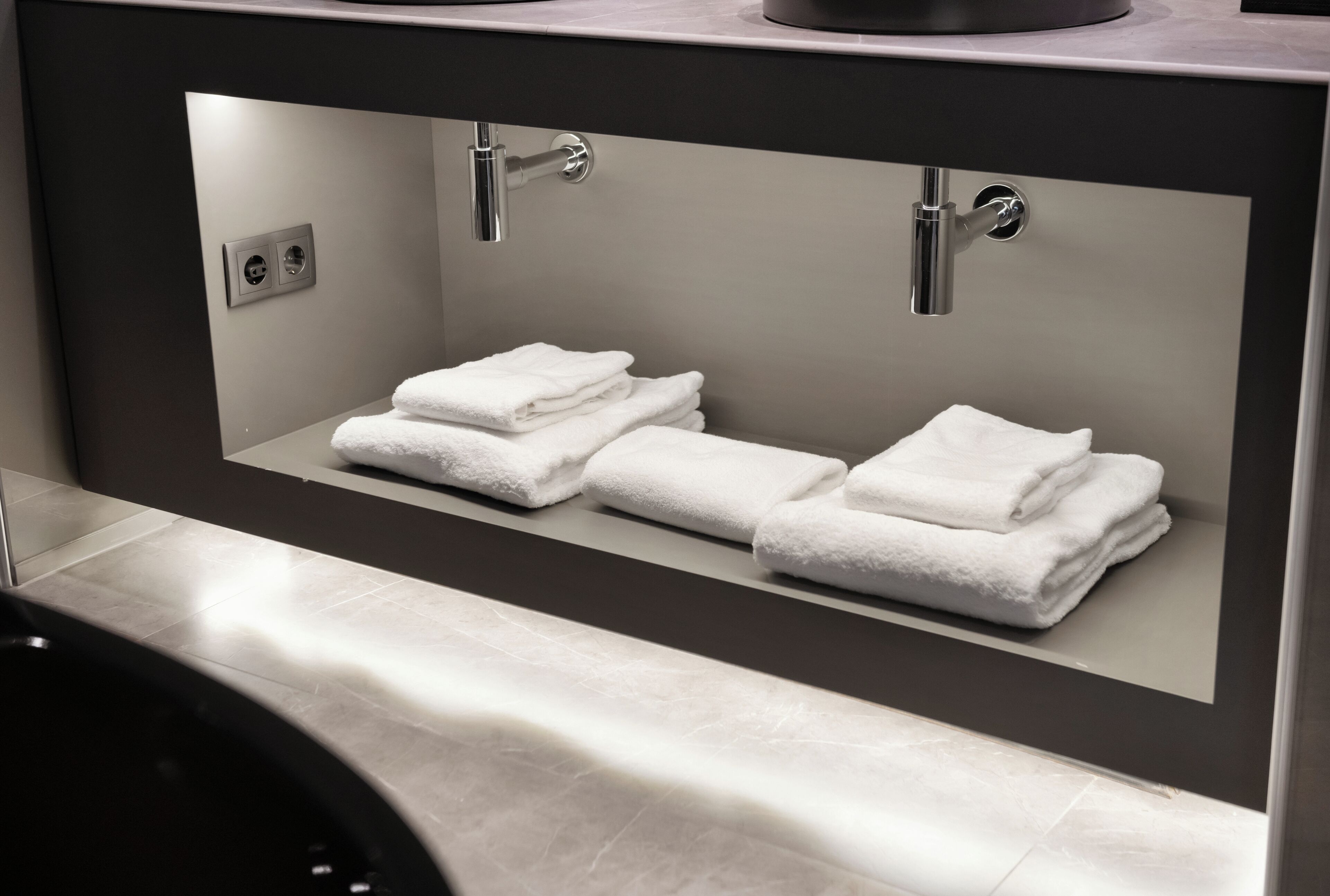 A modern bathroom with a built-in sink, two towel racks, and a mirror.