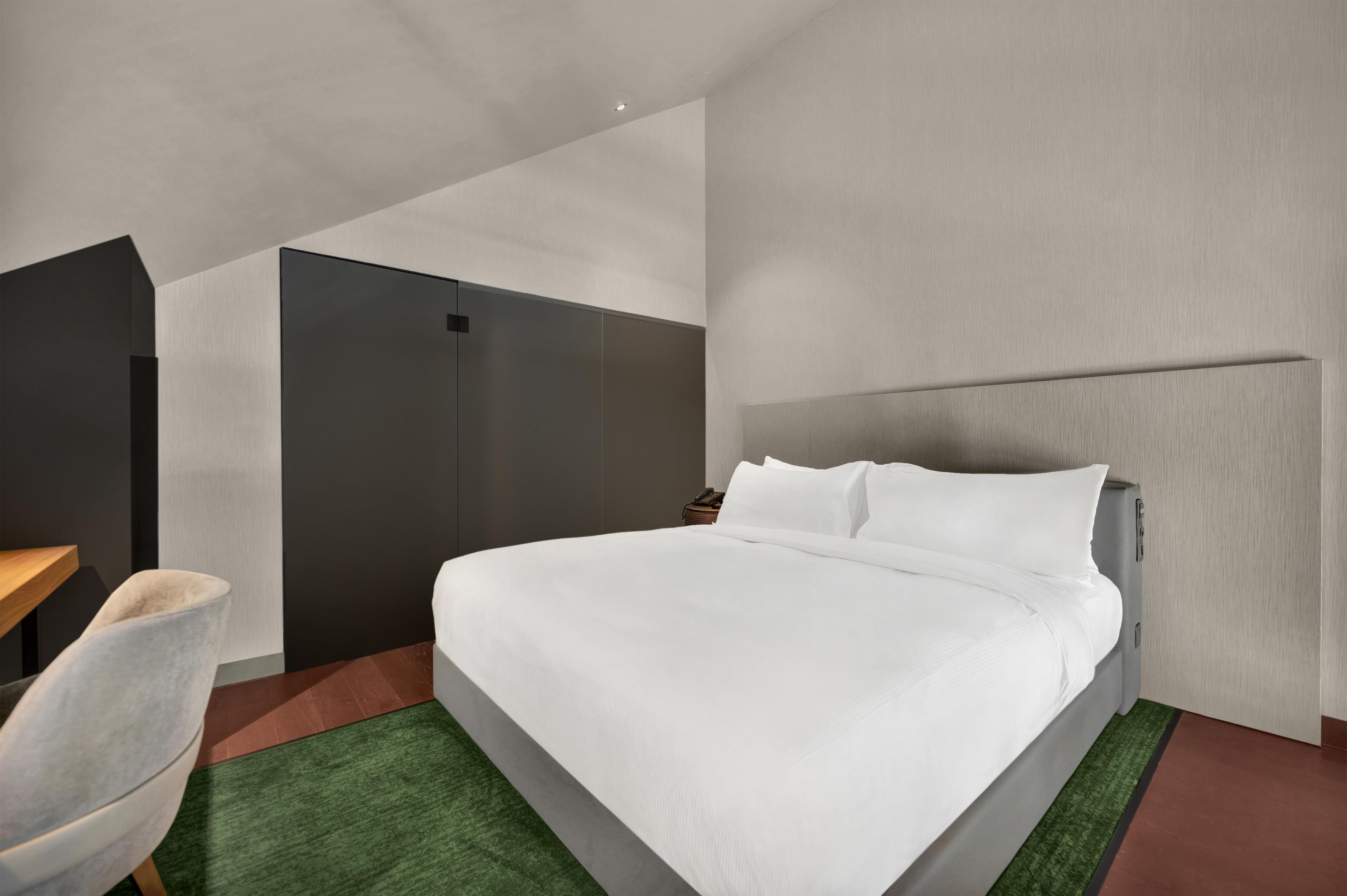 Una habitación de hotel moderna con una cama grande, un escritorio y una silla.