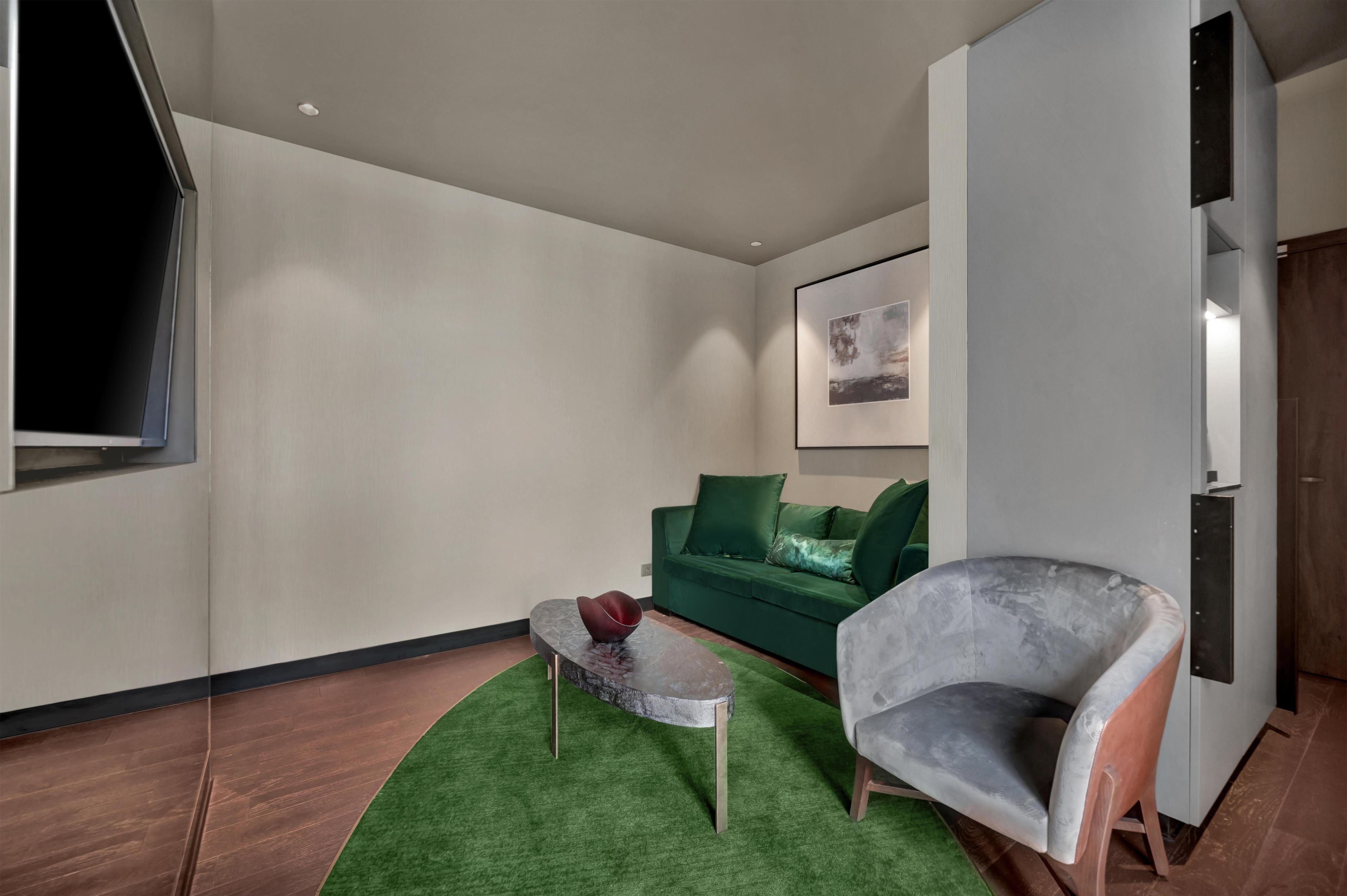 A modern living room with a green sofa, a grey armchair, and a small round table with a decorative item.