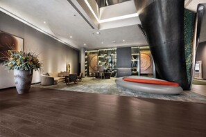 A modern lobby with a large planter, seating area, and a unique black column. - Hilton Porto Gaia (Vila Nova de Gaia)
