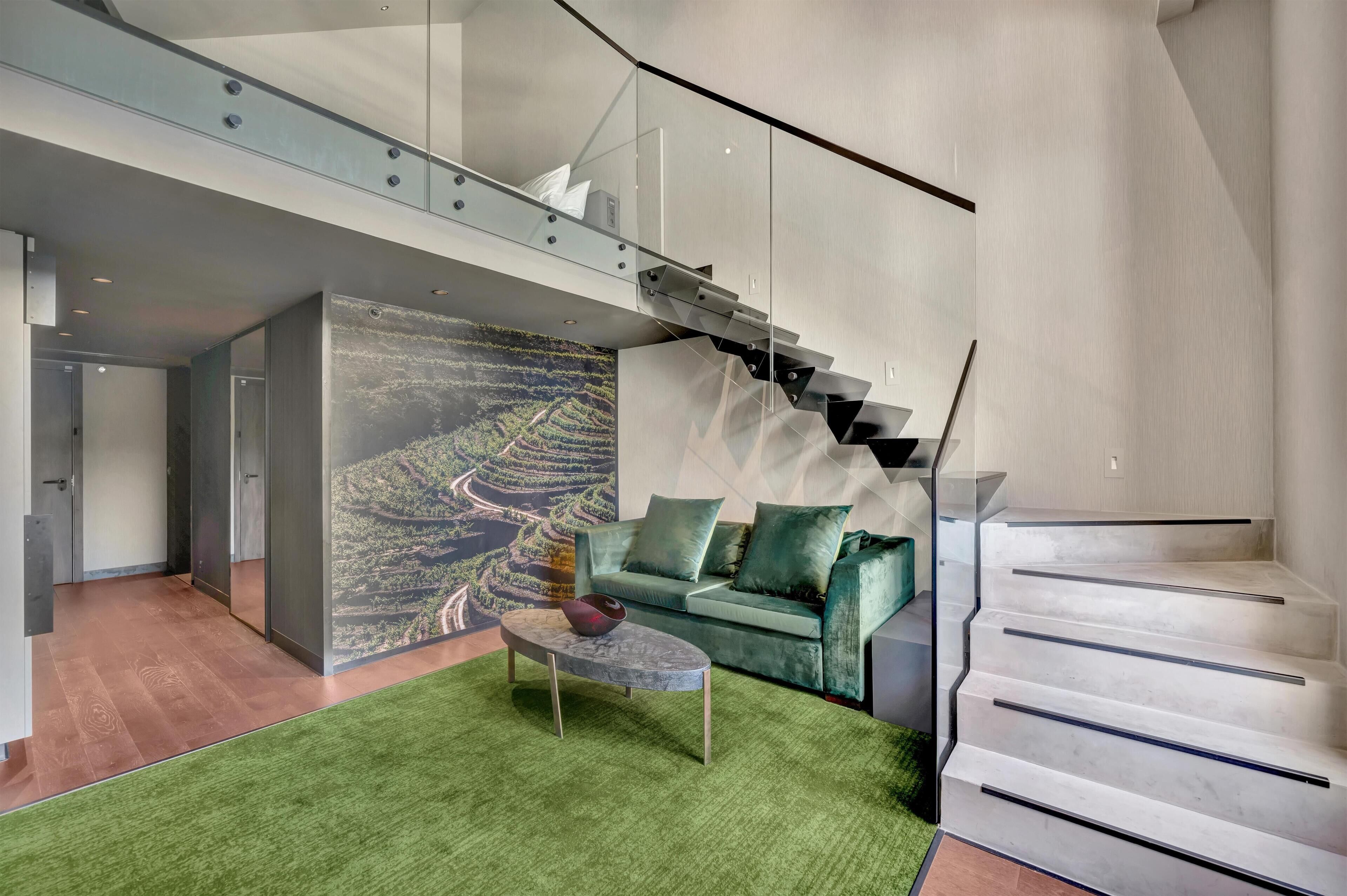 A modern interior with a green sofa, a coffee table, and a staircase.